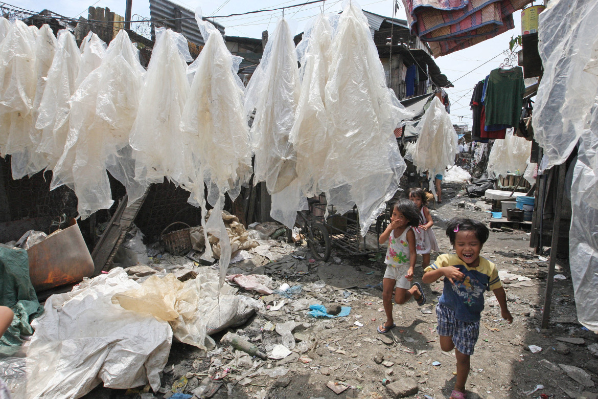 Filipino children run through plastic bags that have been washed and dried