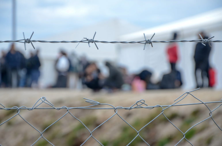 barbed wire surrounds refugee camp