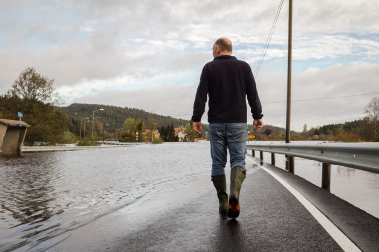 Man walking on flooded road in Kristiansted, Norway.