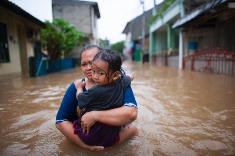 Woman, child walk through Jakarta floodwaters