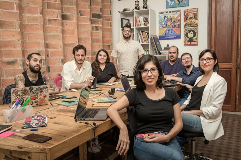 Fotografía de la sala de redacción de El Surtidor, con los cofundadores Alejandro Valdez (de pie en el centro) y Jazmín Acuña (de pie atrás). Imagen: cortesía de El Surtidor