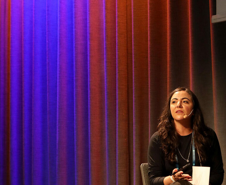 Brazilian journalist Juliana dal Piva sits on stage to moderate the session on political extremism at GIJC23.