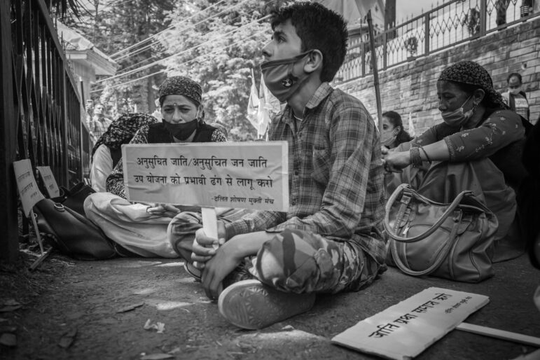 A boy sitting on ground with a placard with slogans during a protest held by people of dalit community outside the HP Vidhan Sabha over their demands.