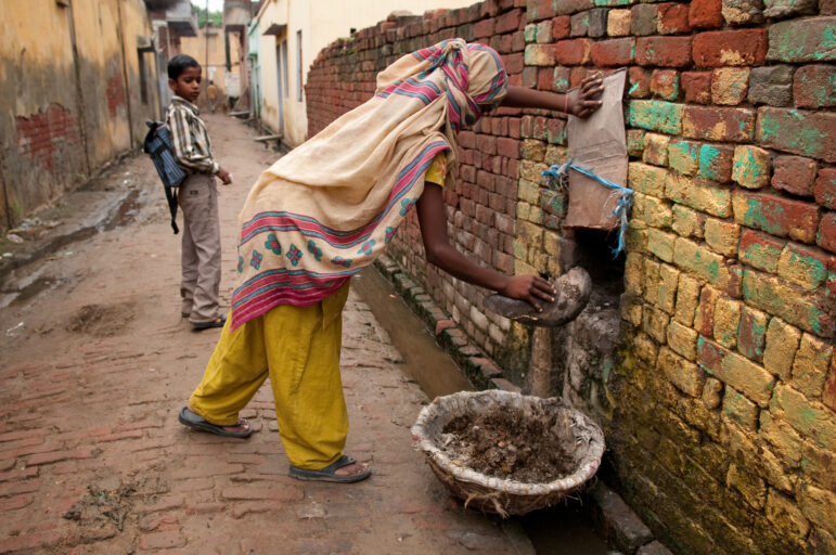 Untouchable woman practicing manual scavenging, or collecting human waste by hand. 