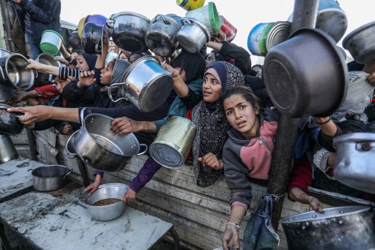 People gather to receive meals from the Rafah charitable kitchen as Palestinians face famine in Khan Yunis, in the southern Gaza Strip, on January 2, 2025