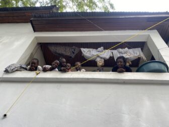 Una antigua escuela en Puerto Príncipe que ahora funciona como campo de refugiados. Una mujer que huyó del barrio de Solino mira desde el segundo piso del edificio con sus hijos, donde ahora viven. Imagen: Cortesía de Juan José Martínez D'Aubuisson